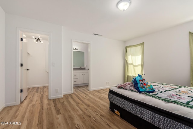 bedroom featuring visible vents, ensuite bath, light wood-style floors, baseboards, and a chandelier
