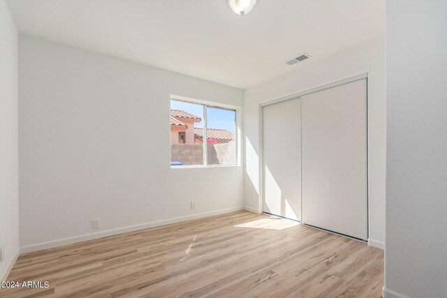 unfurnished bedroom featuring a closet and light hardwood / wood-style floors