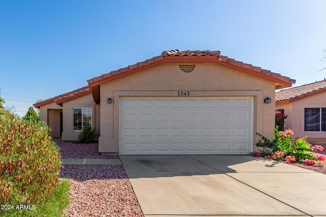 view of front of property featuring a tile roof, a garage, driveway, and stucco siding