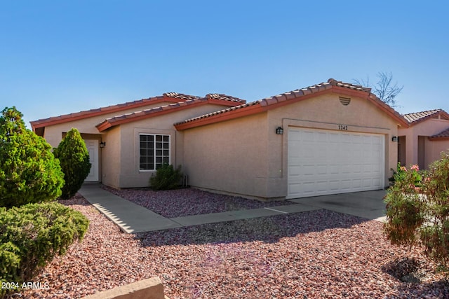 mediterranean / spanish house featuring a tile roof, an attached garage, driveway, and stucco siding