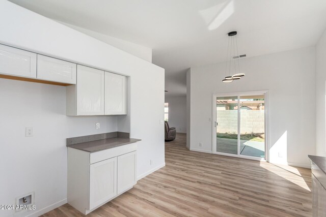 kitchen featuring decorative light fixtures, white cabinets, and light hardwood / wood-style floors