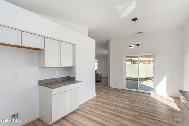 kitchen with visible vents, hanging light fixtures, white cabinetry, dark countertops, and light wood-type flooring