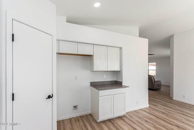 kitchen with white cabinetry, light hardwood / wood-style flooring, and lofted ceiling