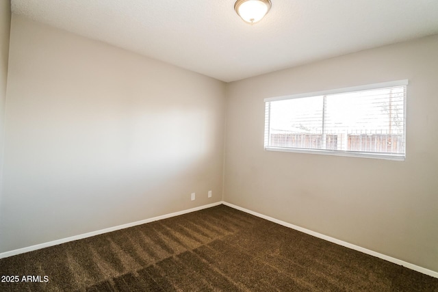 empty room with dark colored carpet and baseboards