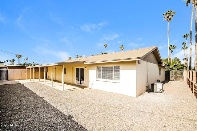 rear view of property with stucco siding, a patio, a fenced backyard, and central air condition unit