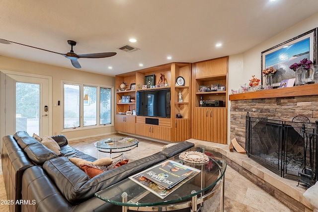 living room with a stone fireplace and ceiling fan