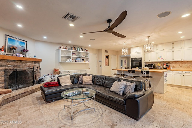 living room with ceiling fan and a stone fireplace