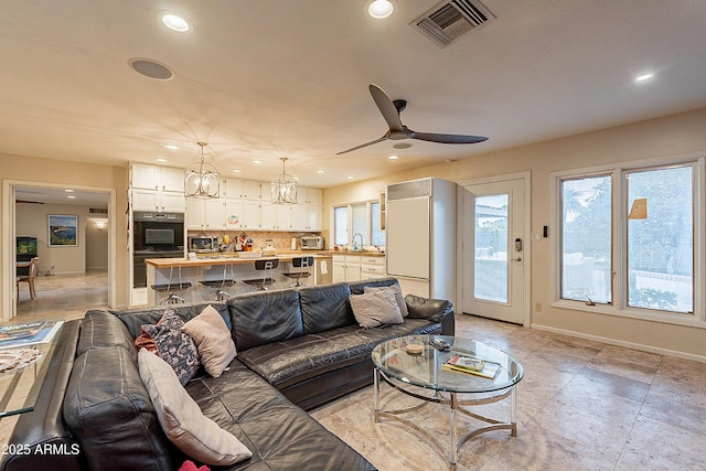 living room featuring sink and ceiling fan with notable chandelier