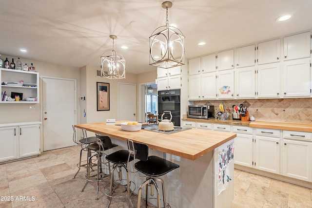 kitchen featuring wood counters, white cabinetry, hanging light fixtures, double oven, and a kitchen island