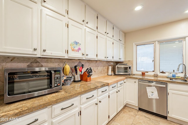 kitchen featuring white cabinetry, dishwasher, sink, and decorative backsplash