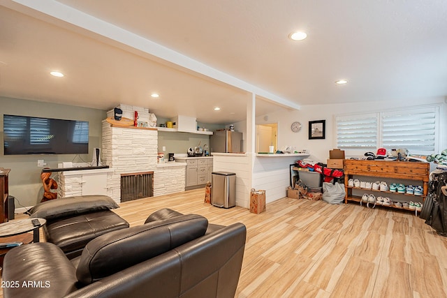 living room with a fireplace, beamed ceiling, and light wood-type flooring