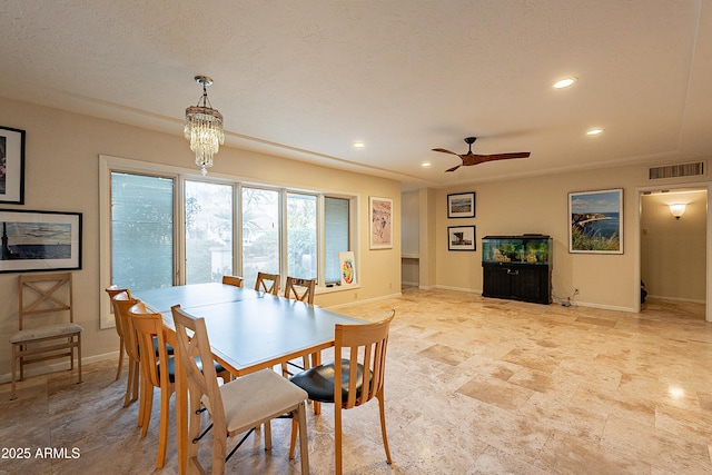 dining room with ceiling fan with notable chandelier and a textured ceiling