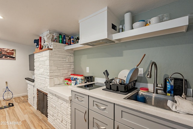 kitchen featuring sink, custom exhaust hood, gray cabinets, and light wood-type flooring