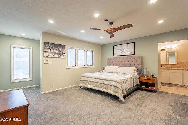 bedroom with connected bathroom, light colored carpet, and ceiling fan