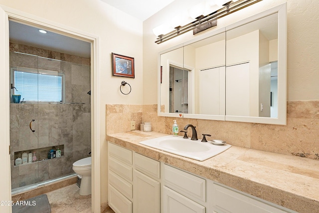 bathroom with tasteful backsplash, tiled shower, vanity, and toilet