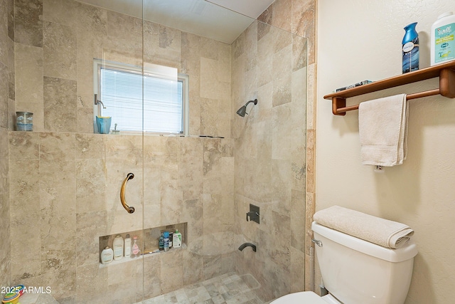 bathroom featuring a tile shower and toilet