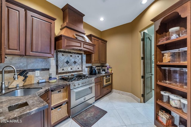 kitchen featuring custom exhaust hood, sink, decorative backsplash, light tile patterned floors, and appliances with stainless steel finishes