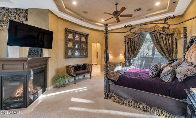 bedroom with carpet flooring, ceiling fan, and a raised ceiling