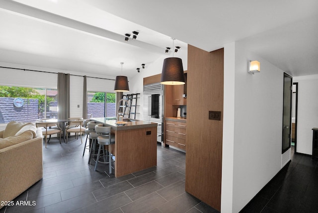 4800 N 68th St Unit 101, Scottsdale, AZ 85251 - kitchen featuring built in fridge, a breakfast bar area, a kitchen island with sink, brown cabinets, and modern cabinets