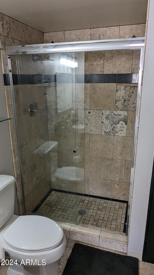 bathroom with an enclosed shower, tile floors, and toilet