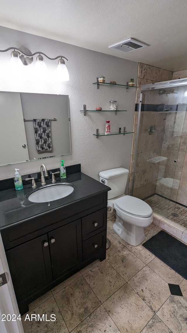 bathroom featuring toilet, an enclosed shower, tile flooring, oversized vanity, and a textured ceiling