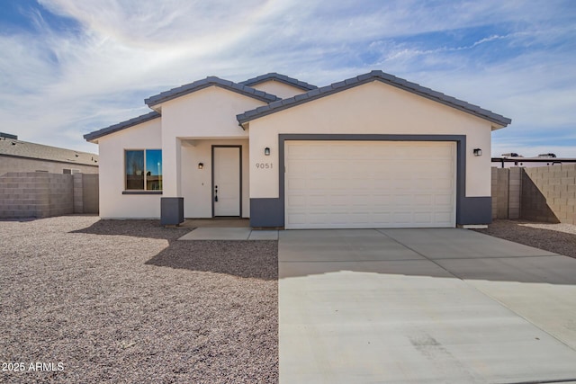 view of front facade with fence, driveway, an attached garage, and stucco siding