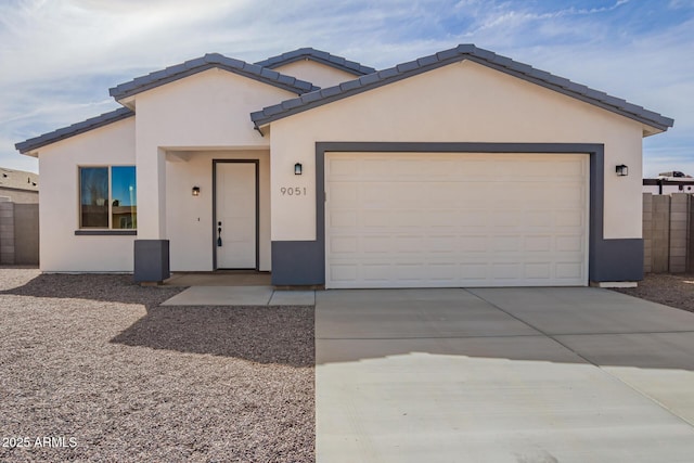 view of front of house with driveway, an attached garage, fence, and stucco siding