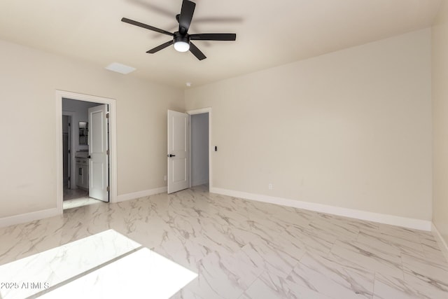 empty room with marble finish floor, a ceiling fan, and baseboards