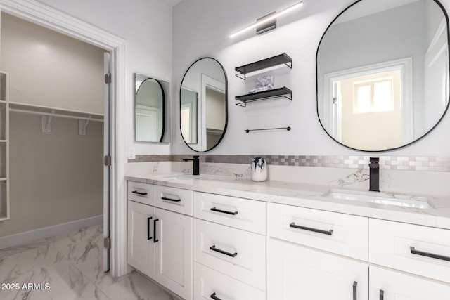 full bath featuring a walk in closet, marble finish floor, a sink, and double vanity