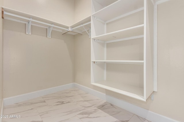 walk in closet featuring marble finish floor