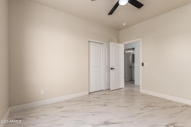 spare room featuring marble finish floor, a ceiling fan, and baseboards