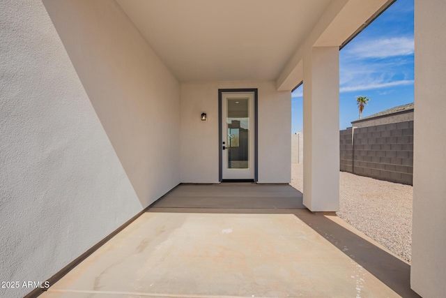 doorway to property with a patio area, fence, and stucco siding