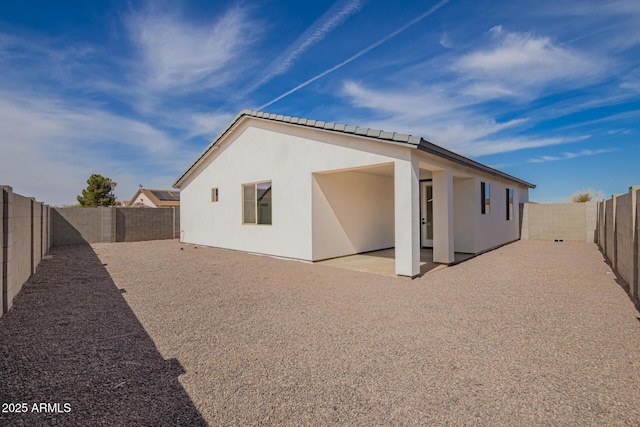 rear view of house featuring stucco siding, a fenced backyard, and a patio