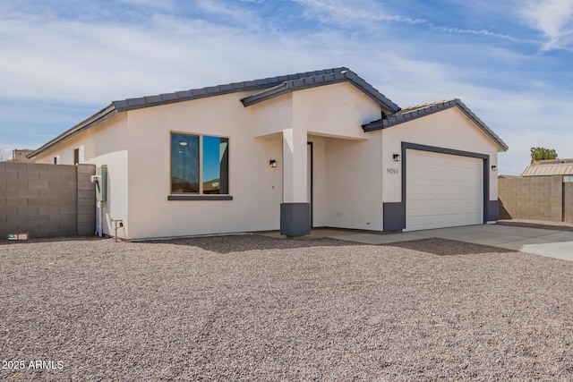 view of front of home with a garage, a tile roof, fence, concrete driveway, and stucco siding