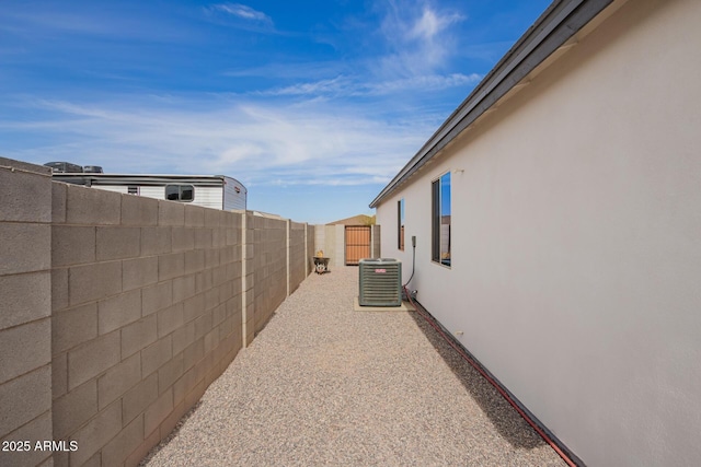 view of side of home with a fenced backyard, cooling unit, and stucco siding