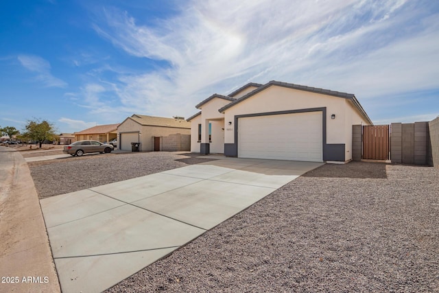 single story home with concrete driveway, an attached garage, a gate, fence, and stucco siding