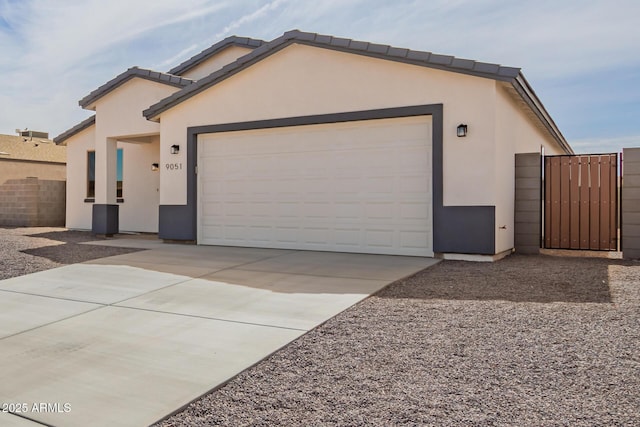 view of front of property with a garage, a gate, driveway, and stucco siding