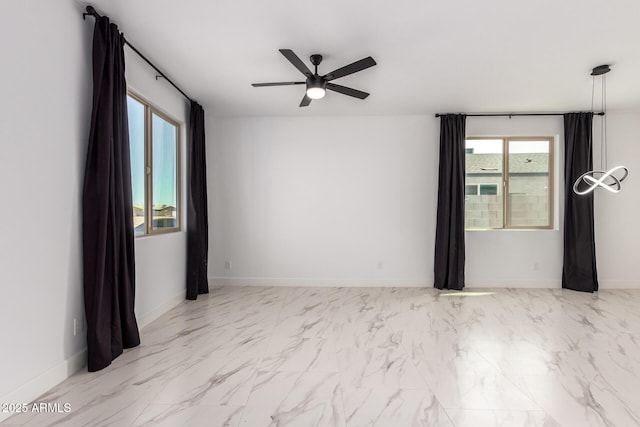 empty room featuring marble finish floor, baseboards, and a ceiling fan