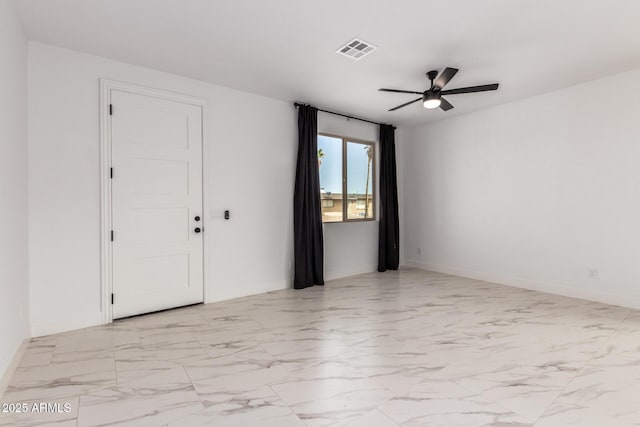 empty room featuring a ceiling fan, marble finish floor, visible vents, and baseboards