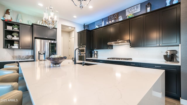 kitchen featuring under cabinet range hood, stainless steel appliances, a spacious island, a sink, and hanging light fixtures