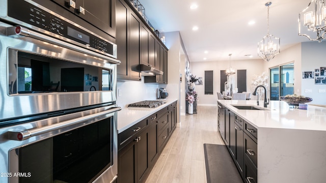 kitchen featuring stainless steel appliances, a sink, light countertops, and under cabinet range hood