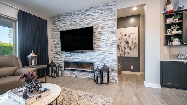 living area featuring wood tiled floor, a fireplace, and baseboards