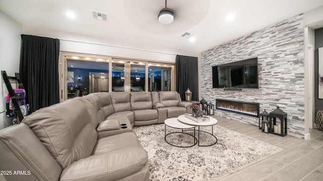 living room featuring a ceiling fan, wood tiled floor, visible vents, and a tiled fireplace