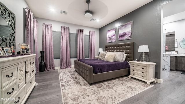 bedroom featuring ceiling fan, wood finished floors, visible vents, and baseboards