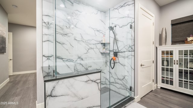 full bathroom with baseboards, a marble finish shower, and wood finished floors