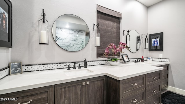 full bathroom featuring double vanity, baseboards, and a sink