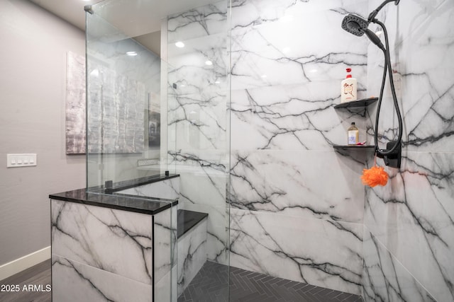 bathroom with wood finished floors, a marble finish shower, and baseboards