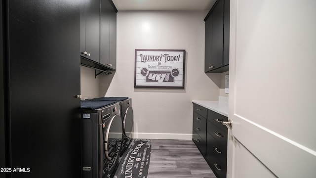 clothes washing area with cabinet space, baseboards, washer and dryer, and wood finished floors