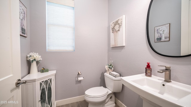 bathroom featuring baseboards, a sink, and toilet