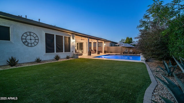 back of property with a patio, a fenced backyard, a lawn, a fenced in pool, and stucco siding